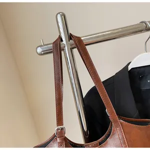 Detail of adjustable straps and silver metal buckles on dark brown leather tote bag