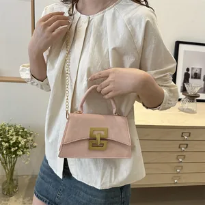 Pink matte crossbody bag with gold geometric buckle and chain strap shown on model
