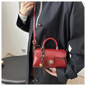 Dettaglio borsa retrò in pelle rosso scuro con chiusura dorata e ciondolo a campanello