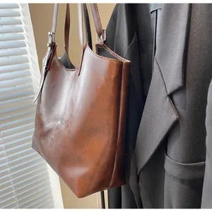 Detail of adjustable strap and vintage dark brown waxed leather texture on tote bag