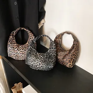 Trois sacs hobo tendance à imprimé léopard en beige, gris et marron sur une étagère