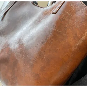 Close-up of vintage brown oil wax leather texture and stitching on a large tote bag