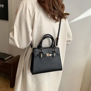 Elegant black matte leather handbag with gold metal clasp shown on female model
