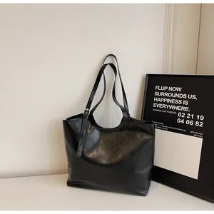 Detail of adjustable silver buckle on black glossy leather tote bag with thin shoulder strap