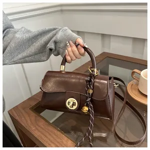 Dettaglio borsa vintage in pelle PU marrone con chiusura a scatto e ciondolo intrecciato
