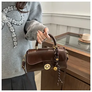 Dettaglio della borsa vintage in PU marrone con chiusura dorata e ciondolo tessuto