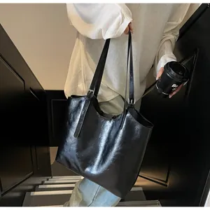 Detail of adjustable metal buckle and glossy leather strap on a black tote bag