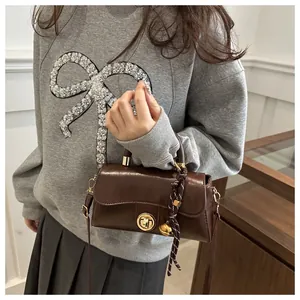 Dettaglio borsa vintage in pelle marrone con fibbia dorata e nappa a righe elegante