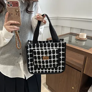 Klassieke zwart-wit geblokte tweed handtas met brede stoffen handvatten en leren label