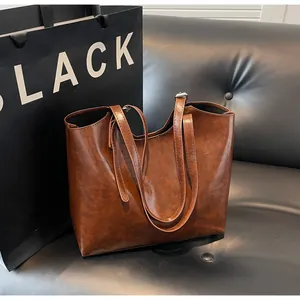 Detail of vintage brown oil wax leather tote bag with slim straps and fine texture