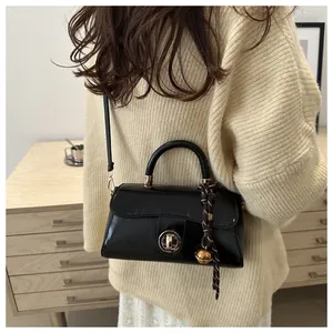 Borsa a tracolla in pelle nera lucida abbinata a un maglione bianco in stile sobrio