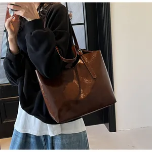 Detailed view of large dark brown oil wax leather tote bag worn on a woman's shoulder