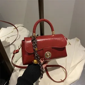 Borsa rossa vintage in pelle con chiusura dorata e accessorio a tracolla a righe