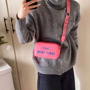 Pink leather camera bag with The Mini Bag print and a geometric patterned strap