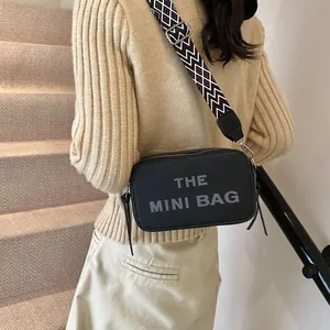 Black pebbled leather mini crossbody camera bag with geometric patterned wide strap