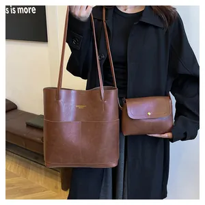 Detail of a brown oil-wax leather tote and matching flap pouch set on a female model