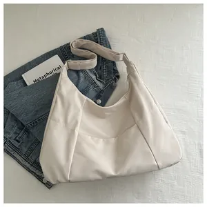 Macro view of ivory hobo bag featuring smooth nylon texture and adjustable shoulder strap