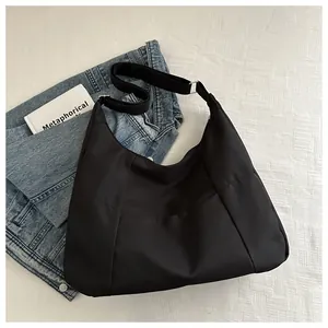 Detailed top view of a black crescent nylon shoulder bag with adjustable wide fabric strap