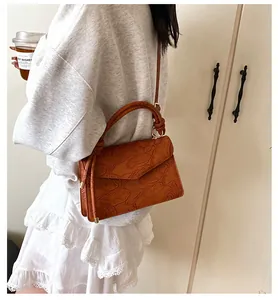 Detail of vintage brown embossed floral PU leather handbag with knot handle and gold hardware