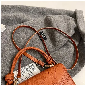 Detail of orange embossed leather handbag with lotus and koi fish patterns and knot handle