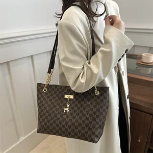 Brown monogram tote bag with gold deer pendant and shoulder strap on white coat model