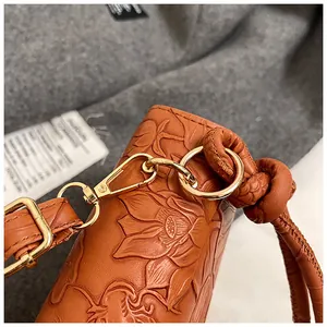 Detailed macro view of orange-brown leather bag with floral embossing and gold hardware