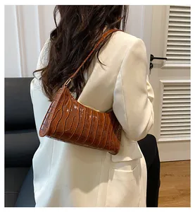 Sac à bandoulière marron motif crocodile porté par un mannequin en studio