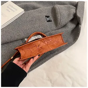 Detailed view of brown leather handbag base featuring embossed lotus pattern and thick texture