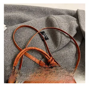 Macro detail of the orange embossed floral pattern and knotted handle on the handbag