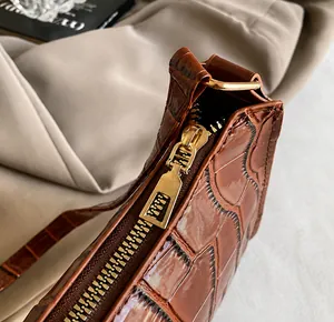 Détail du zip doré lisse sur le sac baguette marron à motif crocodile