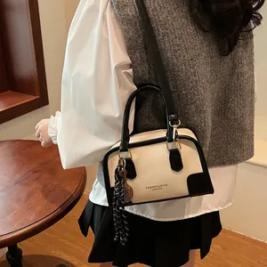 Chic cream and black contrast Boston bag with tennis racket charm and shoulder strap