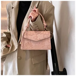 Detail of pink crossbody bag with embossed lotus koi patterns and knotted handle
