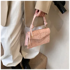 Detail of light pink small square bag featuring embossed lotus and koi fish patterns