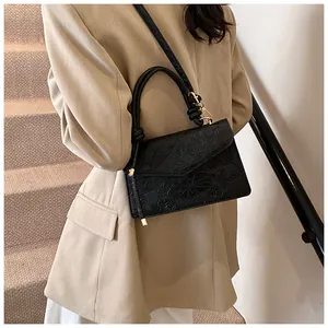 Detail view of the black crossbody bag showing lotus and koi embossed pattern with gold hardware