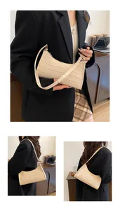 Détail du sac baguette beige avec motif crocodile montrant la texture et la bandoulière