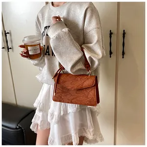 Detailed close-up of brown embossed leather handbag with lotus pattern and knotted handle