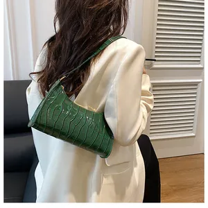 Détail du motif crocodile vert sur un sac à bandoulière vintage en forme de croissant