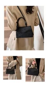Detail of black crossbody bag with embossed lotus and carp pattern on synthetic leather