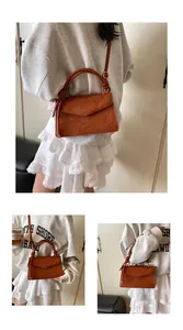 Close-up of brown crossbody bag featuring elegant floral embossed textures and a carry handle