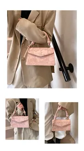 Detail of light pink crossbody bag featuring embossed lotus and carp patterns with rope handle