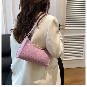 Détail du sac baguette lilas à motif crocodile porté par un mannequin à l'épaule