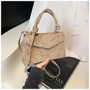 Detail of beige shoulder bag featuring embossed lotus and koi fish artistic patterns