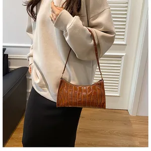 Gros plan du sac baguette marron motif crocodile sur modèle montrant la texture du cuir PU