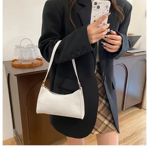 Détail du sac baguette blanc à motif crocodile porté avec un blazer noir chic