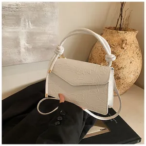 Macro detail of white leather handbag featuring embossed lotus floral pattern and top handle