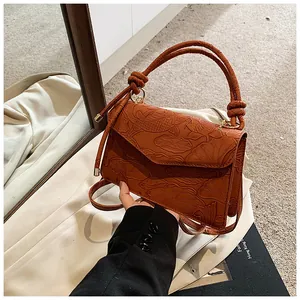 Detailed relief of koi fish and lotus on a brown crossbody bag with woven handles