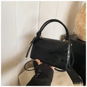 Detail of black handbag featuring embossed lotus and koi fish patterns with a top handle