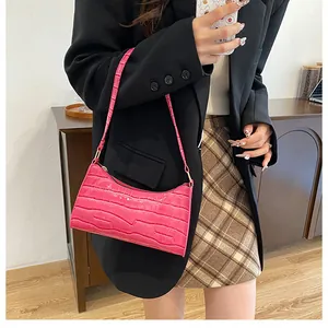 Détail du sac à bandoulière rose à motif crocodile porté à l'épaule pour femme