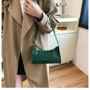 Détail de la texture crocodile vert foncé sur le sac baguette en cuir verni brillant