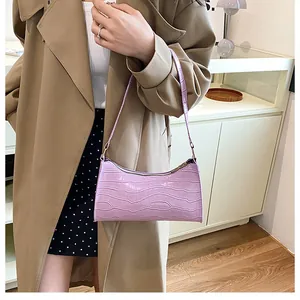 Détail du sac baguette violet à motif crocodile porté avec un trench-coat élégant